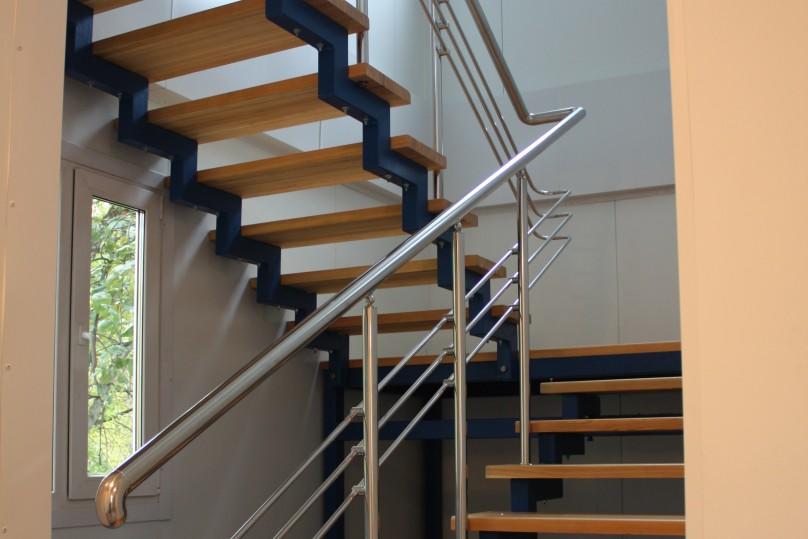 A staircase with wooden steps and a stainless steel handrail